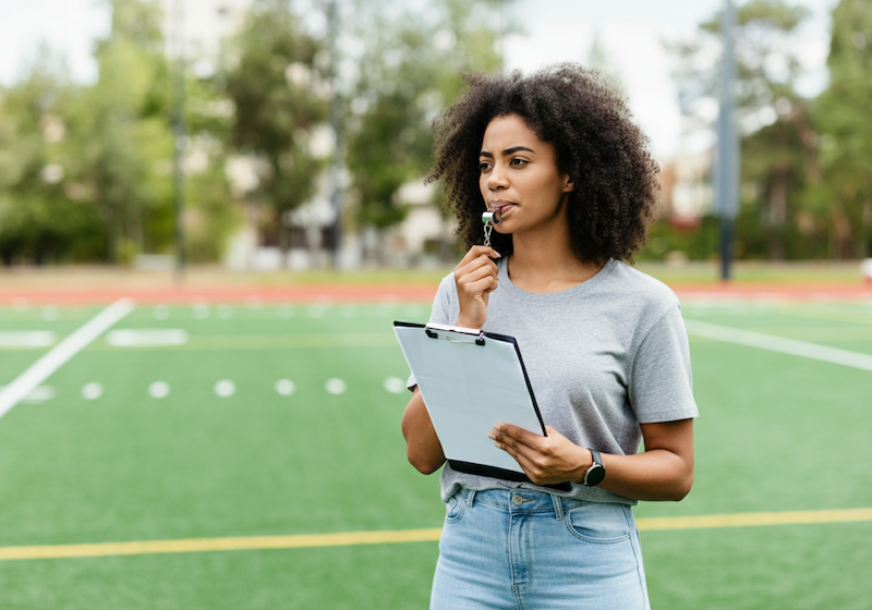 A young female design manager holding a clipboard acting as a coach.
